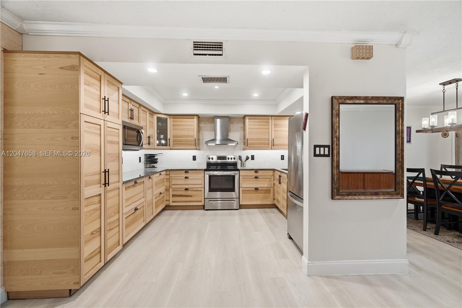 A kitchen features light wood cabinets, stainless steel appliances, and light-colored wood-look flooring — 2822 N 34th Ave, Hollywood FL 33021, HOLLYWOOD, FL