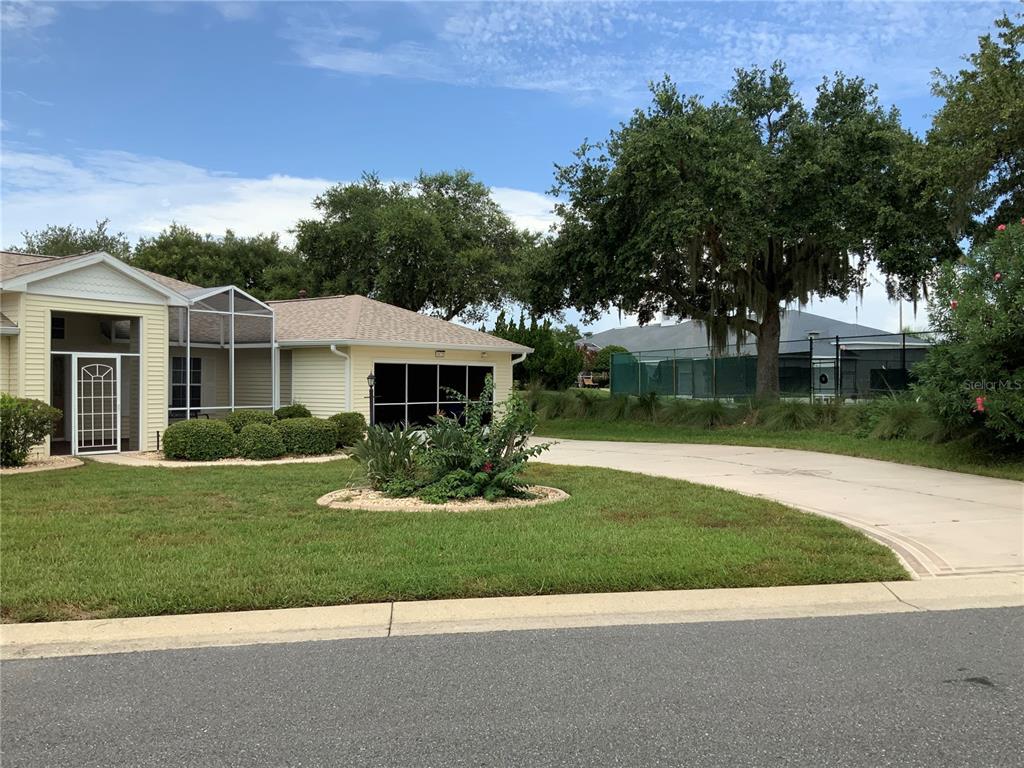 A light yellow house with a screened porch and a driveway leading to a garage — 5475 BOUNTY CIRCLE, TAVARES, FL