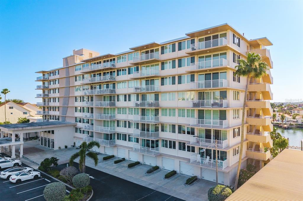 An exterior view of a multi-story residential building with balconies and a parking lot — 223 ISLAND WAY UNIT 2D, CLEARWATER BEACH, FL