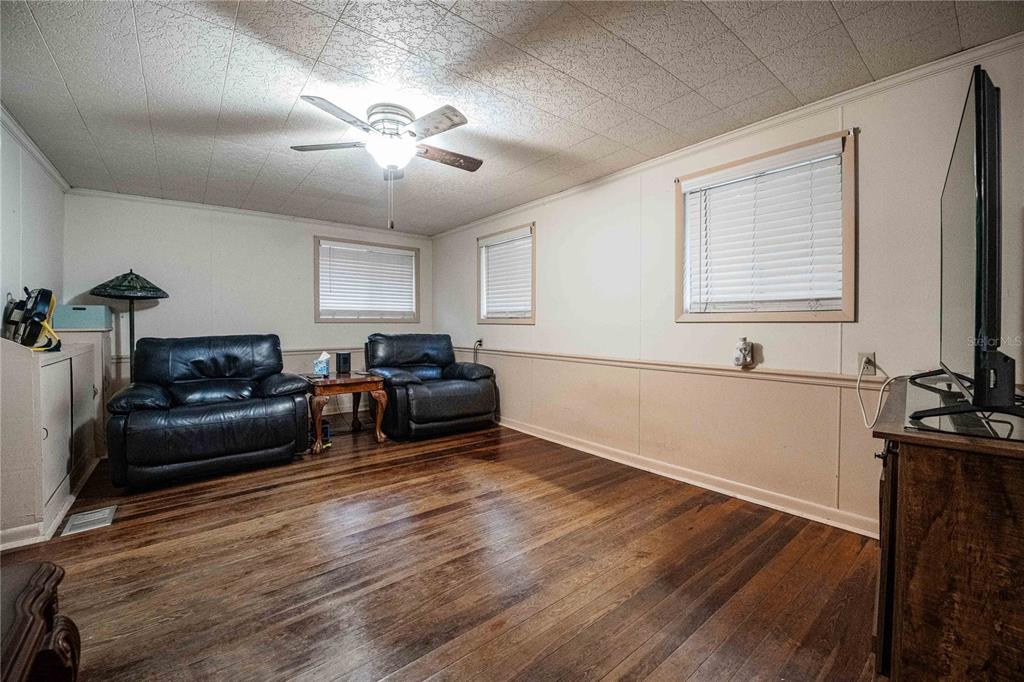 A living room features dark wood flooring, two black leather recliners, and a ceiling fan — 5140 LAKELAND HIGHLANDS ROAD, LAKELAND, FL