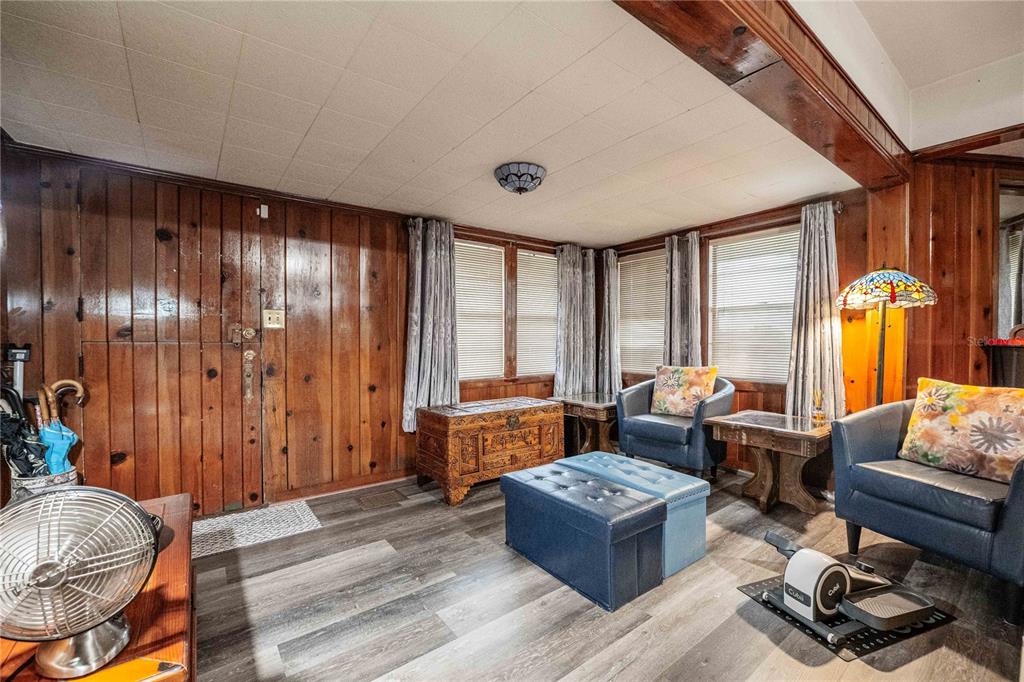 A living room features wood-paneled walls, a white tiled ceiling, and gray wood-look flooring — 5140 LAKELAND HIGHLANDS ROAD, LAKELAND, FL