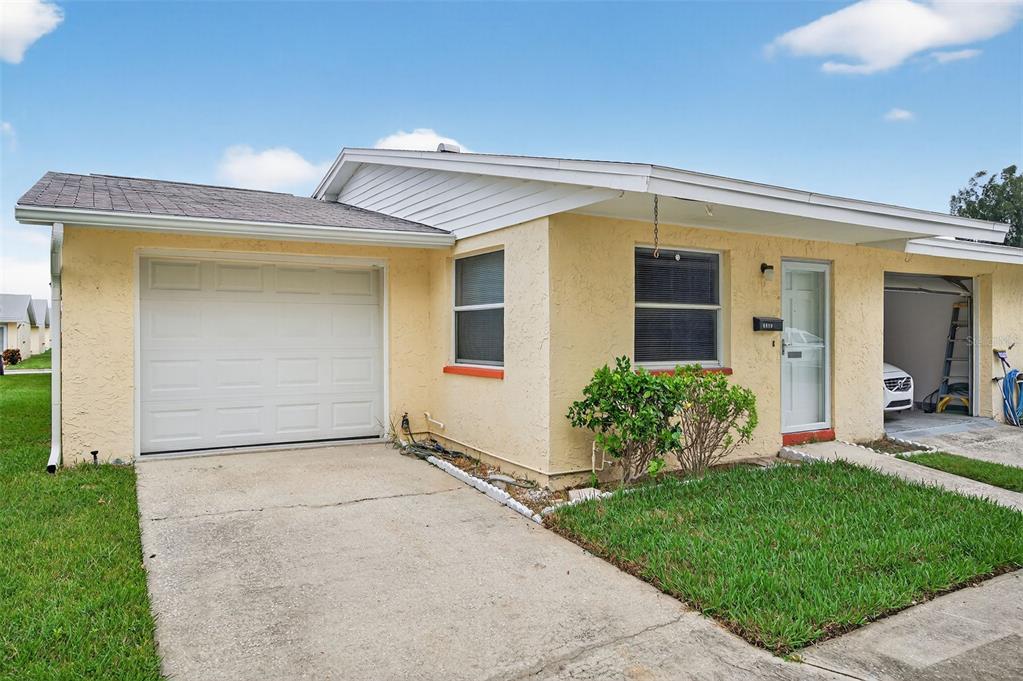 A yellow single-story house with a white garage door, a front door, and a driveway — 4929 DOCNER STREET, NEW PORT RICHEY, FL