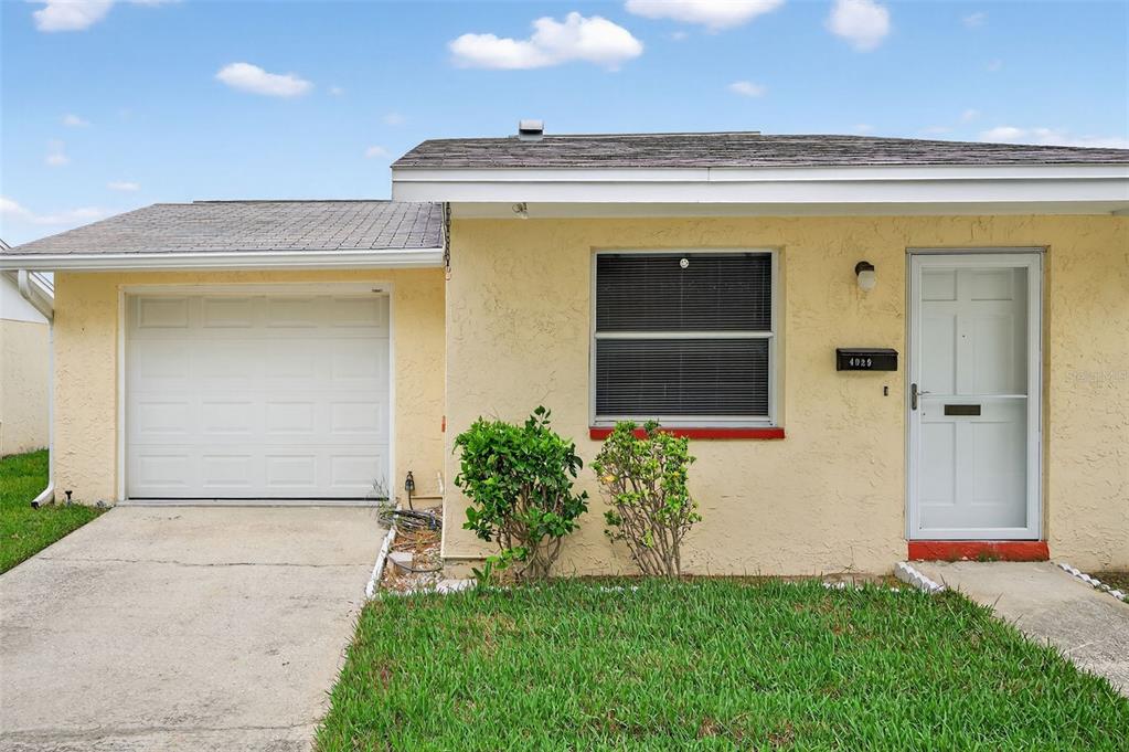 A single-story house with a yellow stucco exterior, a garage, and a front entrance — 4929 DOCNER STREET, NEW PORT RICHEY, FL