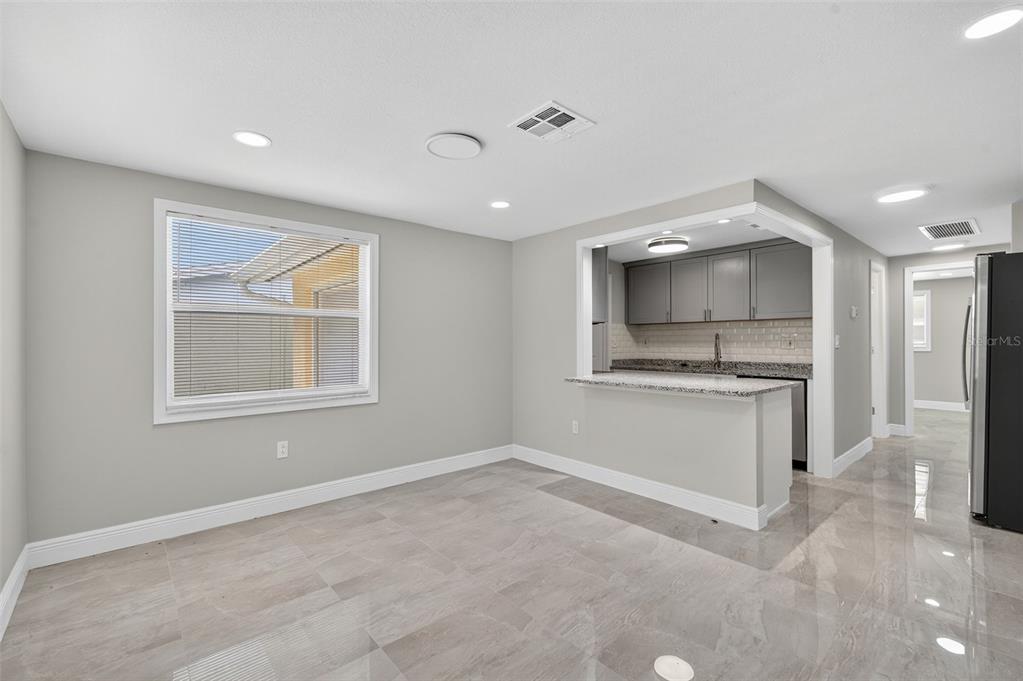 A dining area with gray tile floors and a breakfast bar opening to a kitchen — 4929 DOCNER STREET, NEW PORT RICHEY, FL