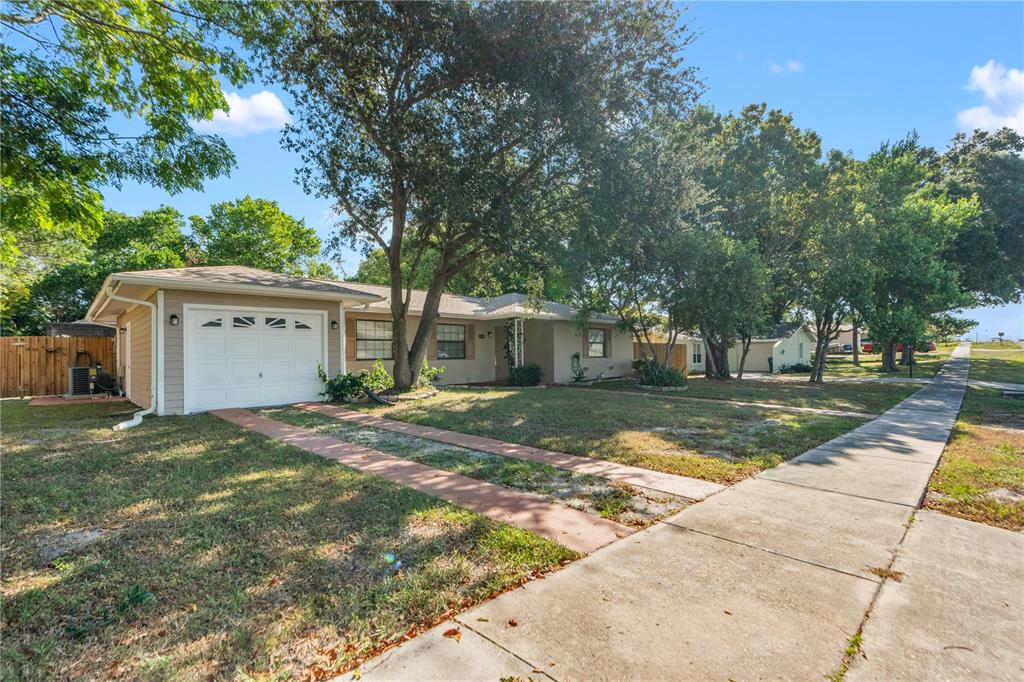 A single-story house with a white garage door, tan siding, and a concrete driveway — 7369 TARRYTOWN DRIVE, SPRING HILL, FL