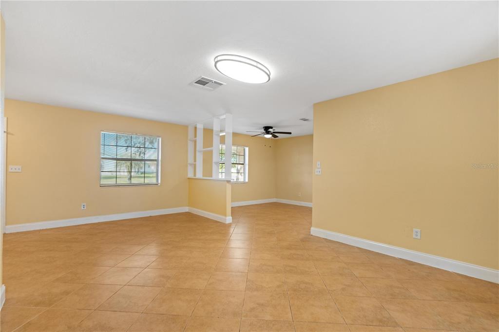 An open living area features yellow walls, tan tile flooring, and a white room divider — 7369 TARRYTOWN DRIVE, SPRING HILL, FL