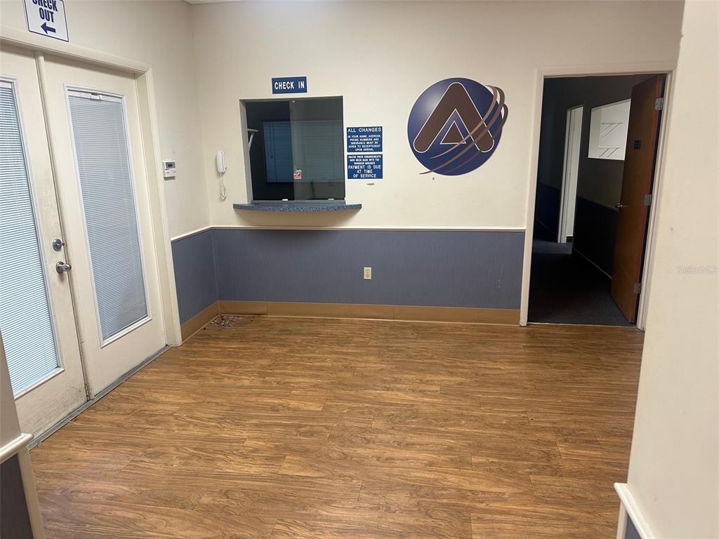 A waiting room features wood-look flooring, a check-in window, and a blue wainscot wall — 4611 NW 53RD AVENUE UNIT A, GAINESVILLE, FL