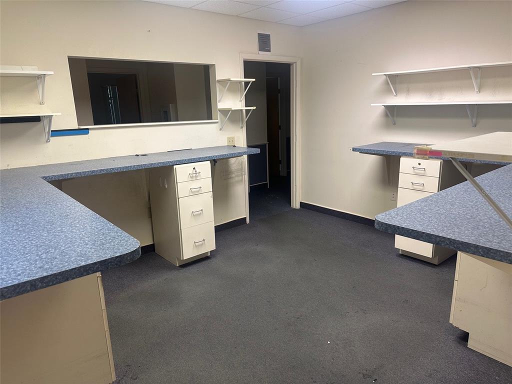 An office or workspace features blue laminate countertops, white storage cabinets, and wall-mounted shelving — 4611 NW 53RD AVENUE UNIT A, GAINESVILLE, FL