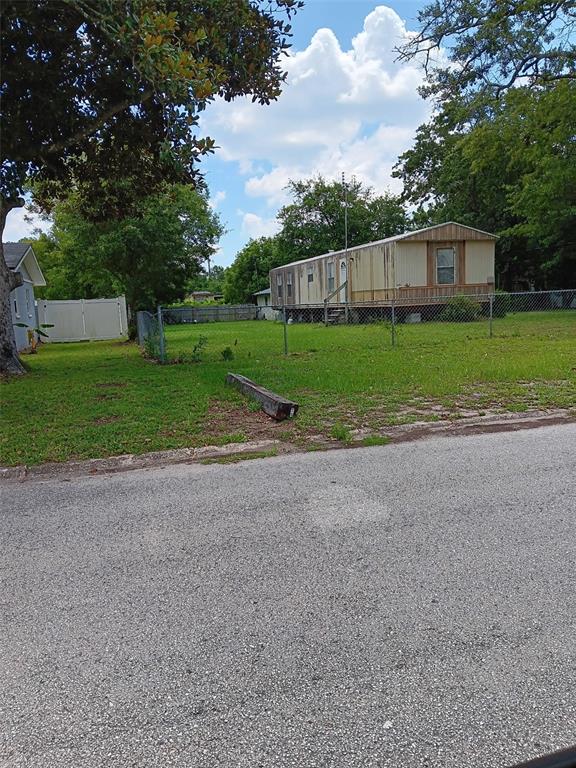 A mobile home sits on a grassy lot behind a chain-link fence near a street — 2153 SUNRISE DRIVE, JACKSONVILLE, FL