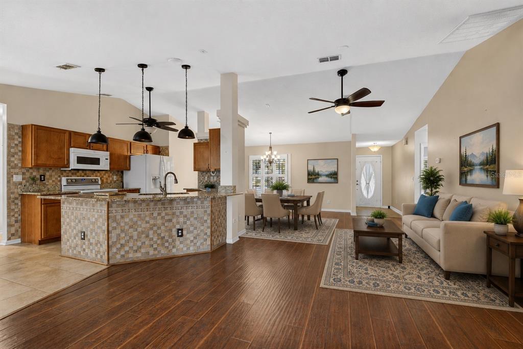 An open-concept living area features a kitchen with a tiled island, dining space, and sofa — 8447 SW 60TH COURT, OCALA, FL