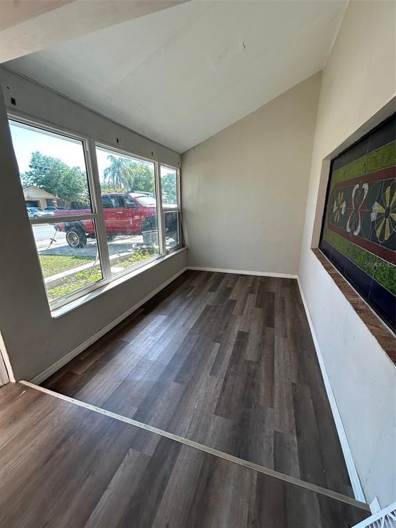 A sunroom features wood-look flooring, large windows, and a decorative wall panel — 7403 FOXBLOOM DRIVE, PORT RICHEY, FL