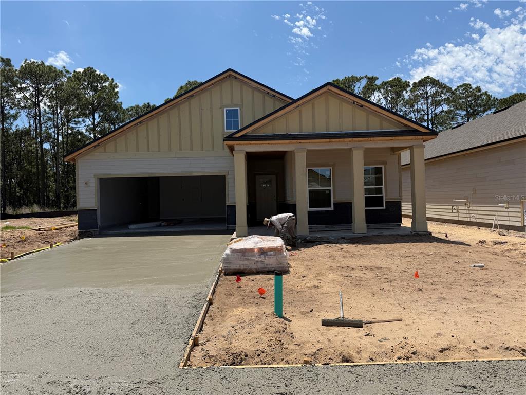 A newly constructed single-story house features a concrete driveway, a covered porch, and board-and-batten siding — 23 PERSEUS AVENUE, FLAGLER BEACH, FL