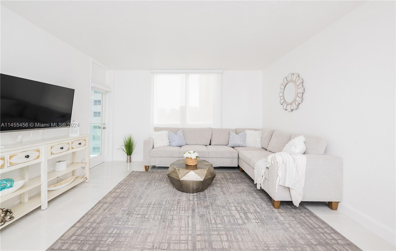 A living room features a light-colored sectional sofa, a geometric coffee table, and a television — 3801 S Ocean Dr # 7O, Hollywood FL 33019, HOLLYWOOD, FL