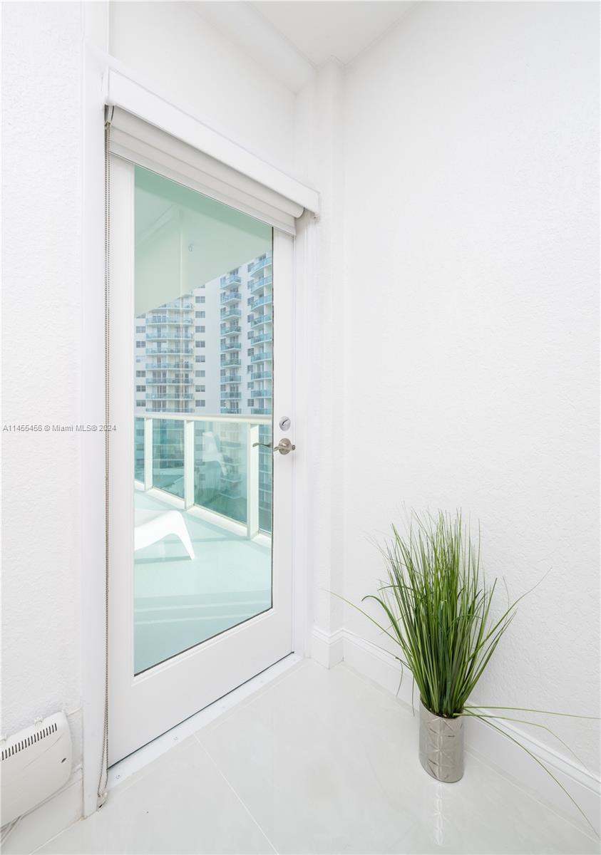 A white-walled room features a glass door leading to a balcony with tall grass — 3801 S Ocean Dr # 7O, Hollywood FL 33019, HOLLYWOOD, FL