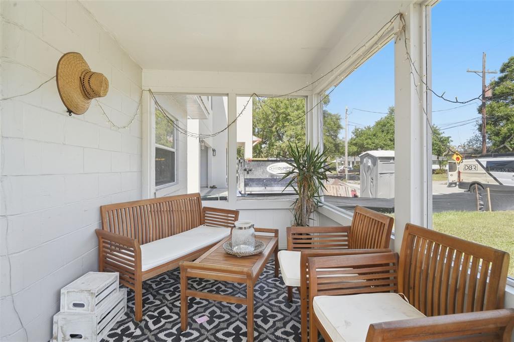 A screened-in porch features wooden furniture, a patterned rug, and a white cinder block wall — 102 W KING STREET, ORLANDO, FL