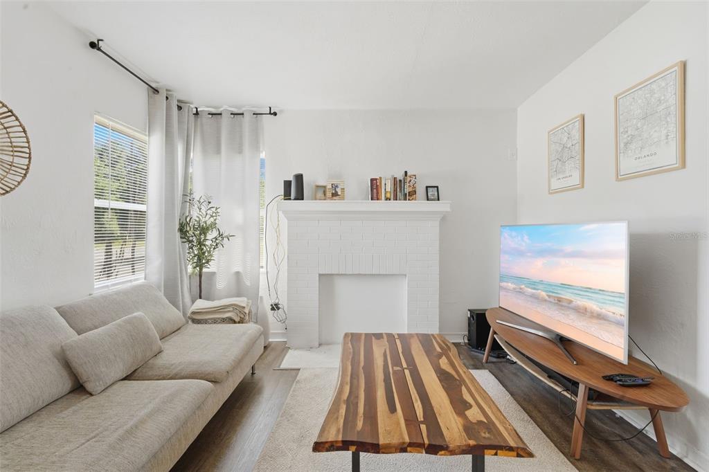 A living room features a white brick fireplace, a wooden coffee table, and a television — 102 W KING STREET, ORLANDO, FL