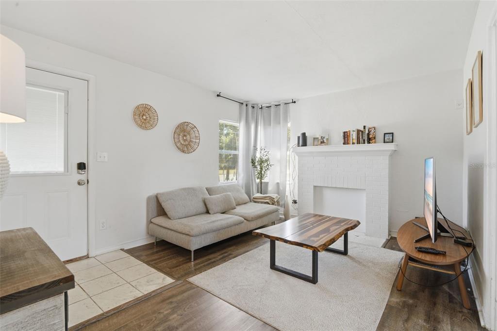 A living room features a white brick fireplace, a light gray sofa, and wood flooring — 102 W KING STREET, ORLANDO, FL