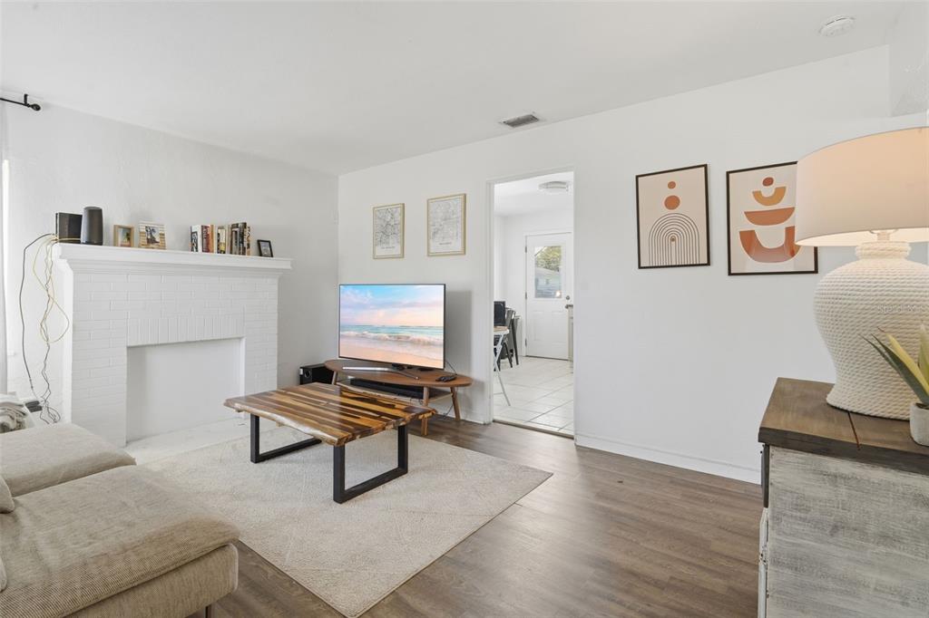 A living room features a white brick fireplace, wood-look flooring, and a coffee table — 102 W KING STREET, ORLANDO, FL