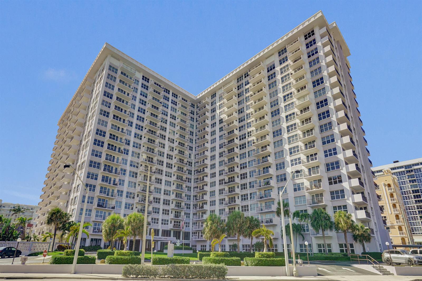 A tall, white, multi-story apartment building with many balconies stands under a clear blue sky — 405 N Ocean Boulevard # 229, Pompano Beach FL 33062, POMPANO BEACH, FL