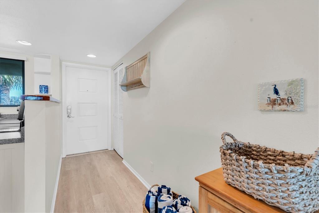 A hallway features light wood-look flooring, a white door, and a woven basket on furniture — 6500 FLOTILLA DRIVE UNIT 187, HOLMES BEACH, FL