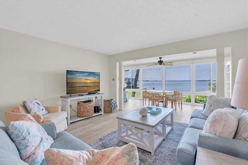 A living room features light wood flooring, a television, and a view of the water — 6500 FLOTILLA DRIVE UNIT 187, HOLMES BEACH, FL