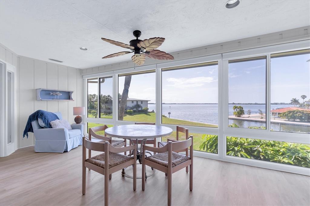 A sunroom with a dining set, ceiling fan, and large windows overlooking a waterfront view — 6500 FLOTILLA DRIVE UNIT 187, HOLMES BEACH, FL