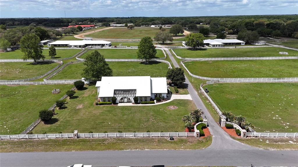 An aerial view shows a white house with a metal roof surrounded by fenced pastures — 4450 SE 216TH AVENUE UNIT Option 2, MORRISTON, FL