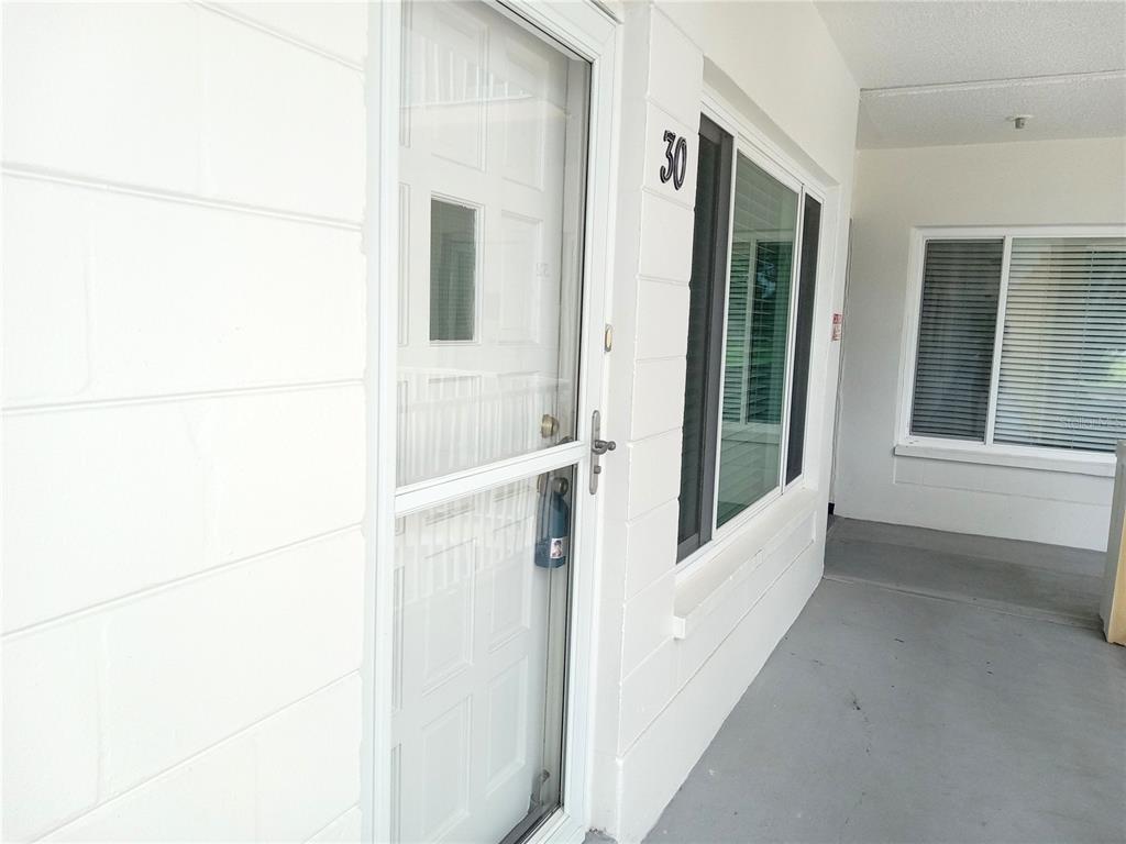 A white exterior wall features a front door with a storm door and number 30 — 2430 FLORENTINE WAY UNIT 30, CLEARWATER, FL