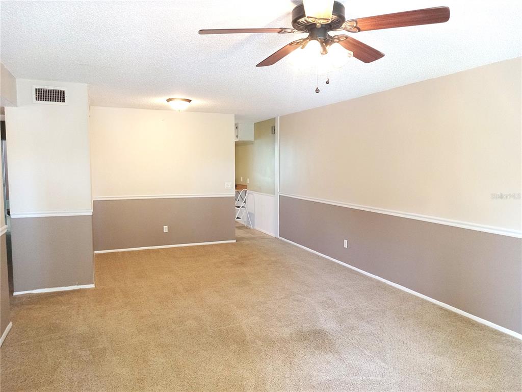 A living room features beige carpet, two-toned walls with chair rail molding, and a ceiling fan — 2430 FLORENTINE WAY UNIT 30, CLEARWATER, FL