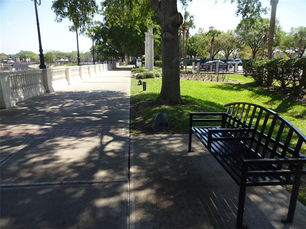 A black metal bench sits on a concrete walkway next to a grassy park area — 123 BLUE POINT WAY UNIT 100, ALTAMONTE SPRINGS, FL
