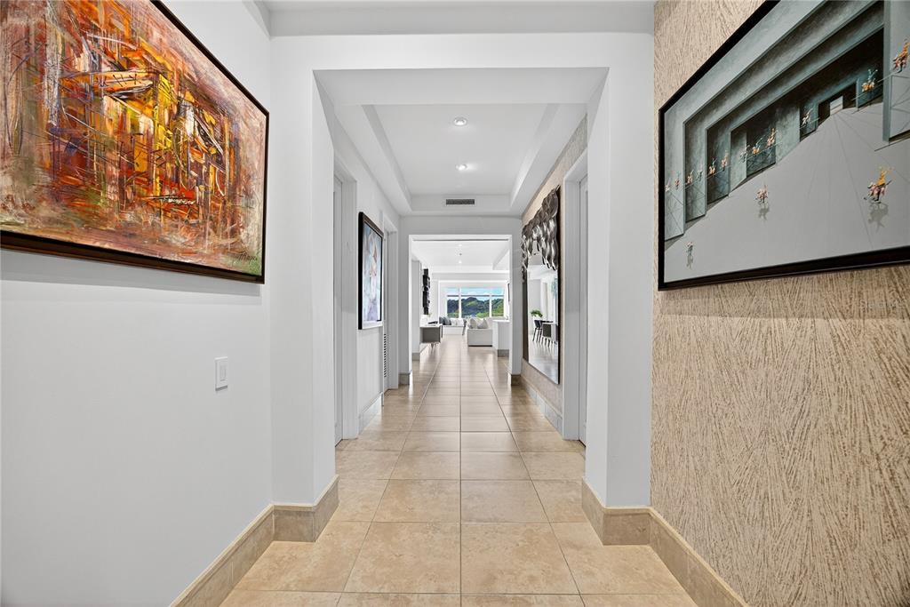 A long hallway with tile floors, white walls, and framed artwork leads to a living area — . COND PLANTATION VILLAGE STREET UNIT 3-303, DORADO, PR