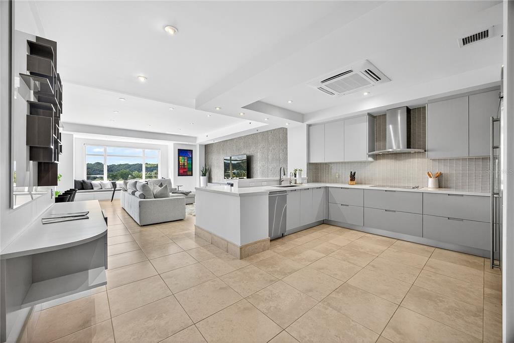 A modern kitchen with grey cabinets and tile floors opens into a living room area — . COND PLANTATION VILLAGE STREET UNIT 3-303, DORADO, PR
