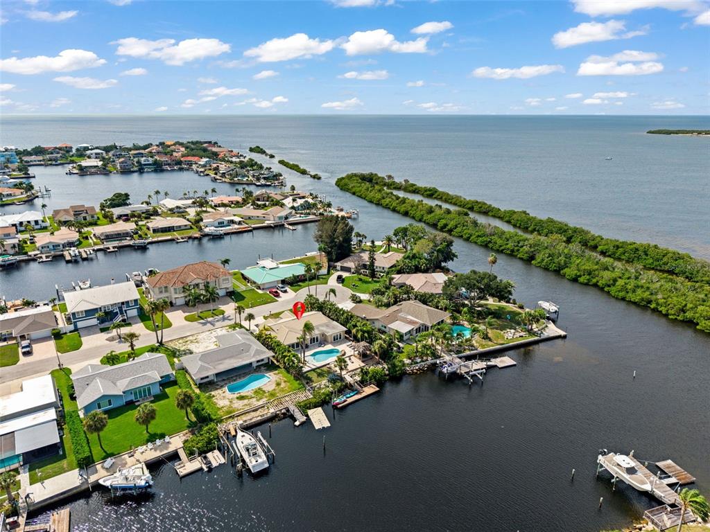An aerial view shows waterfront houses with private docks and swimming pools along a canal — 5548 LEEWARD LANE, NEW PORT RICHEY, FL