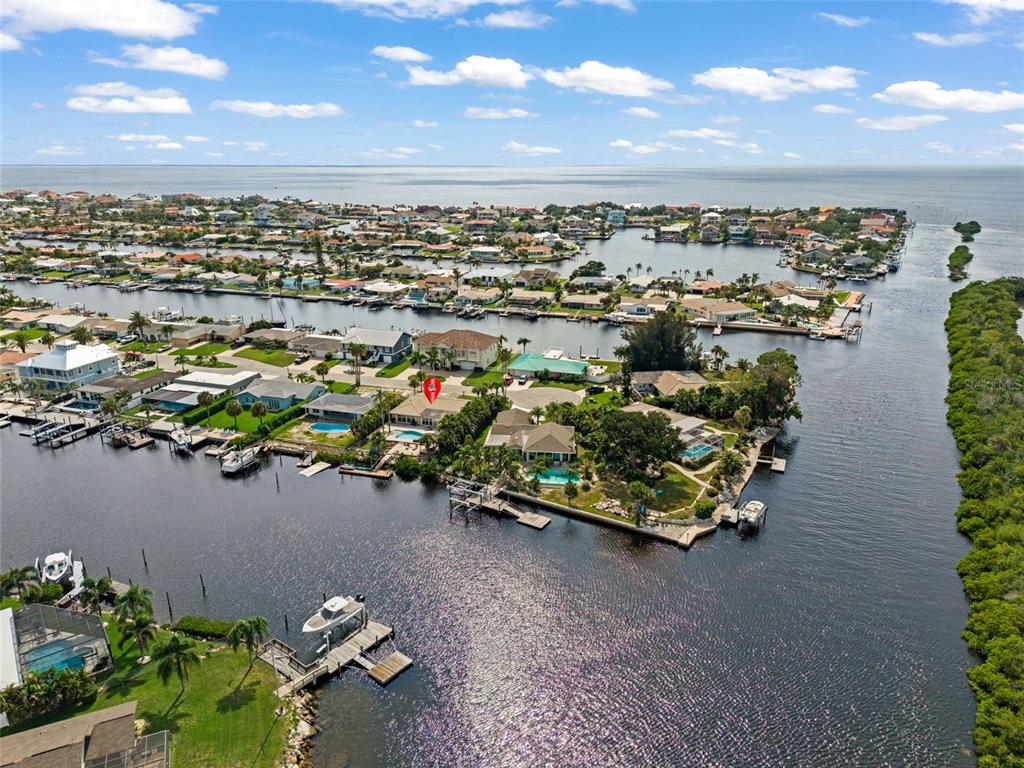 An aerial view shows waterfront homes with docks and swimming pools along a canal — 5548 LEEWARD LANE, NEW PORT RICHEY, FL