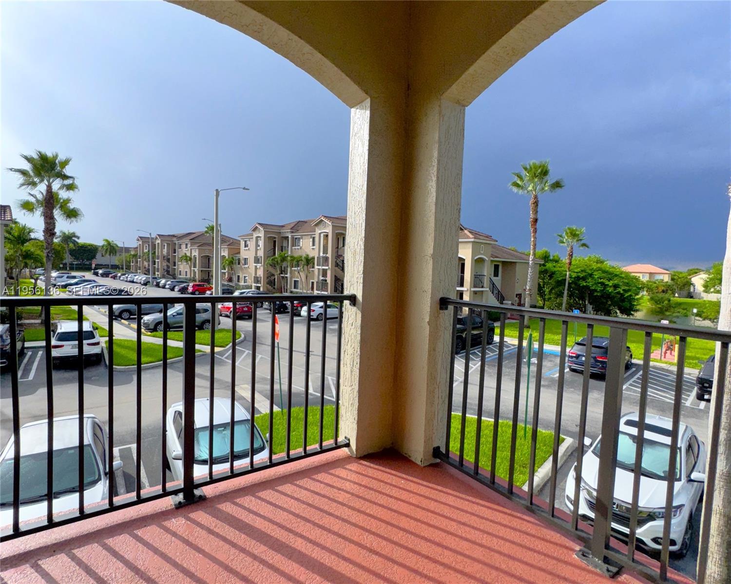 A balcony with a metal railing overlooks a parking lot and apartment buildings — 22441 SW 88th Pl # 5, Cutler Bay FL 33190, CUTLER BAY, FL