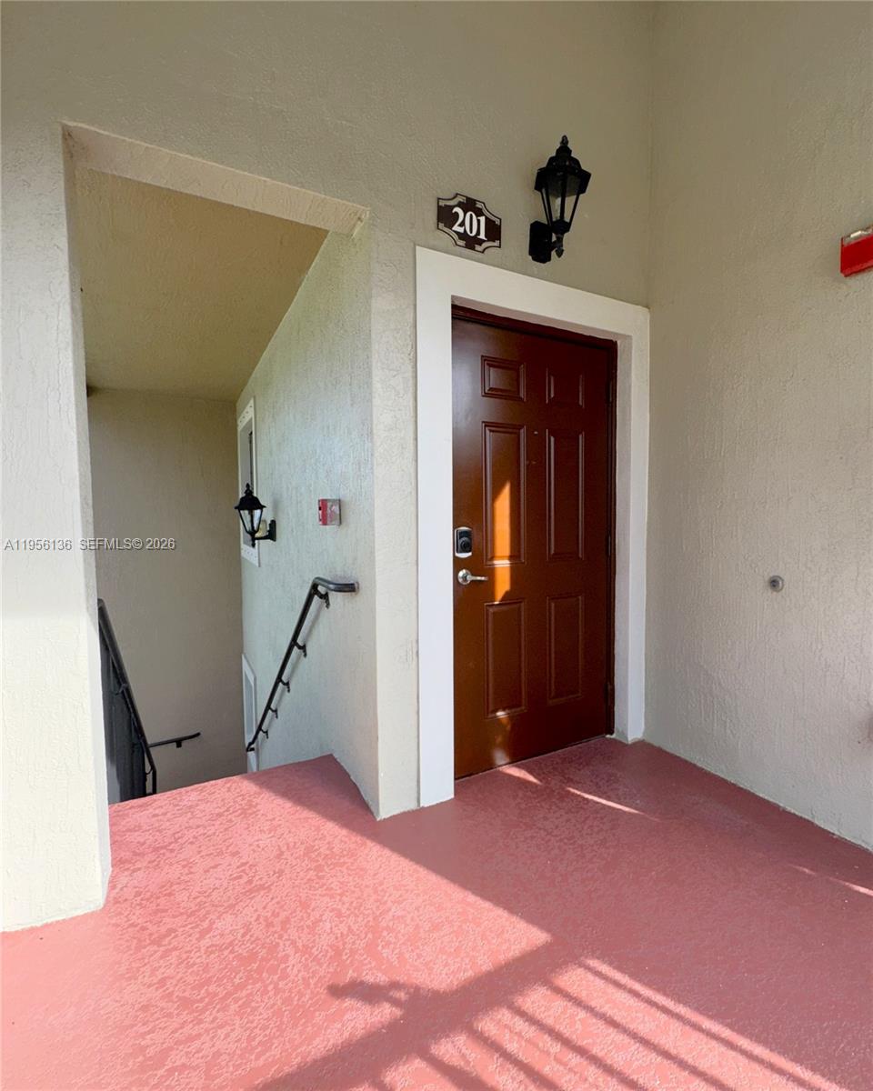 The exterior entrance to unit 201 features a brown door, a wall-mounted light, and stairs — 22441 SW 88th Pl # 5, Cutler Bay FL 33190, CUTLER BAY, FL