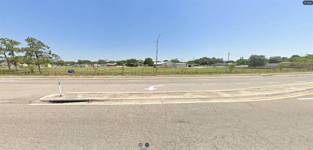 This is an exterior view of a vacant, fenced-in lot along a paved road — HWY 60 E, LAKE WALES, FL