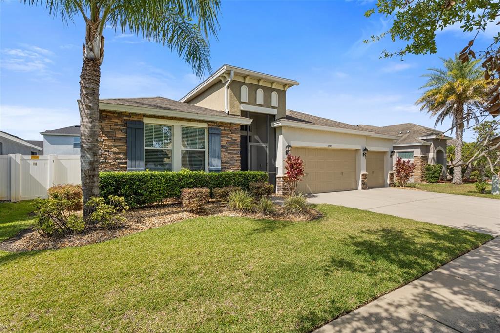 A single-story house with a stone facade, a three-car garage, and a palm tree — 11504 HARLAN EDDY COURT, RIVERVIEW, FL