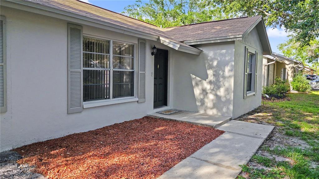 A single-story house with a light-colored exterior, a brown shingled roof, and a front tree — 7419 IVORY TERRACE, NEW PORT RICHEY, FL