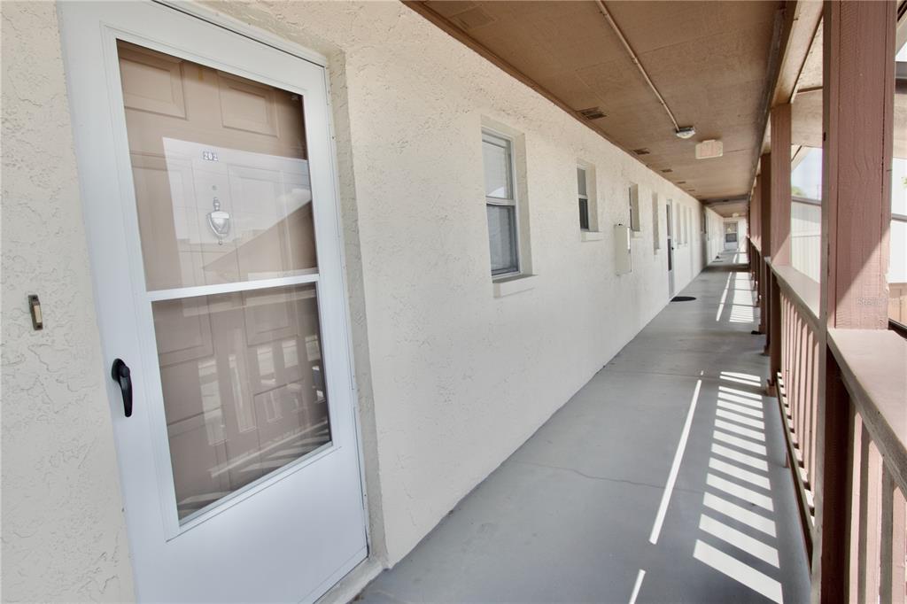 An exterior view of an apartment building walkway with a door labeled 202 — 5135 GEMSTONE DRIVE UNIT 202, NEW PORT RICHEY, FL