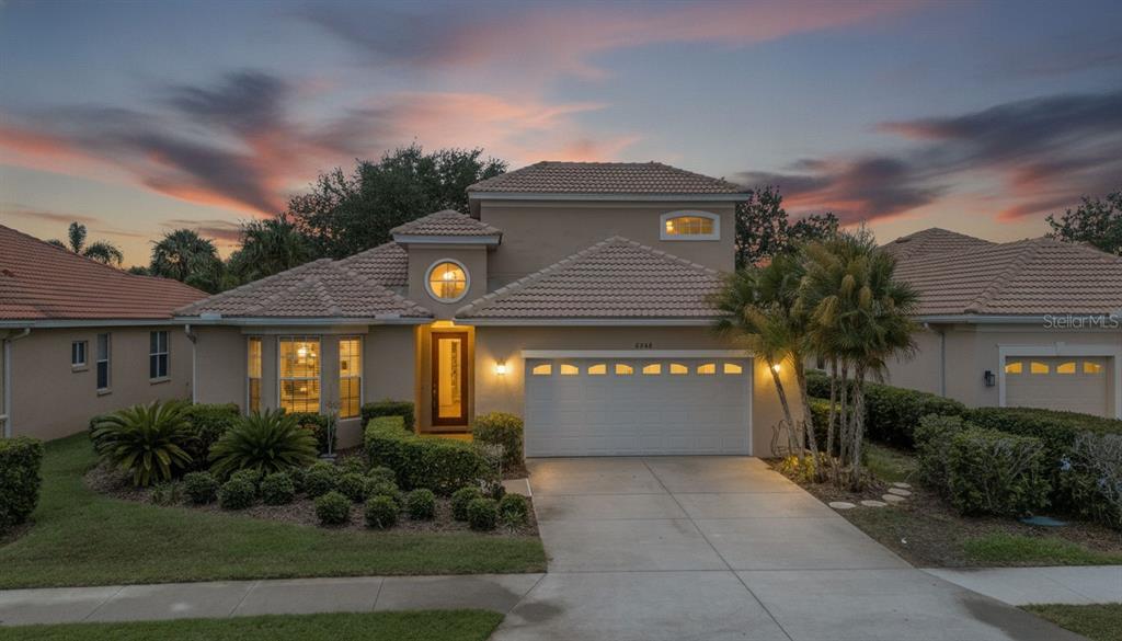 A two-story suburban house with a two-car garage and a landscaped front yard at sunset — 6348 ROOKERY CIRCLE, BRADENTON, FL