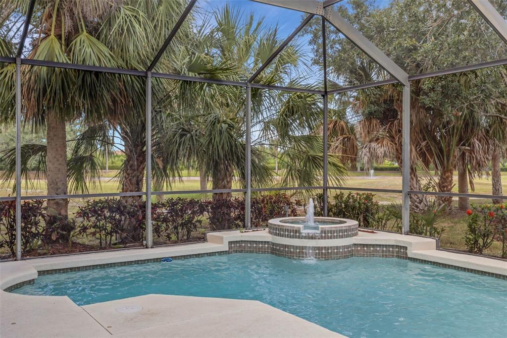 A screened-in pool area features a raised spa with a fountain spilling into the pool — 6348 ROOKERY CIRCLE, BRADENTON, FL