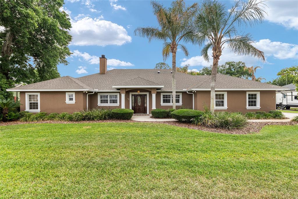 A single-story brown house with a shingled roof and palm trees sits on a lawn — 29 SE OCALE WAY, SUMMERFIELD, FL