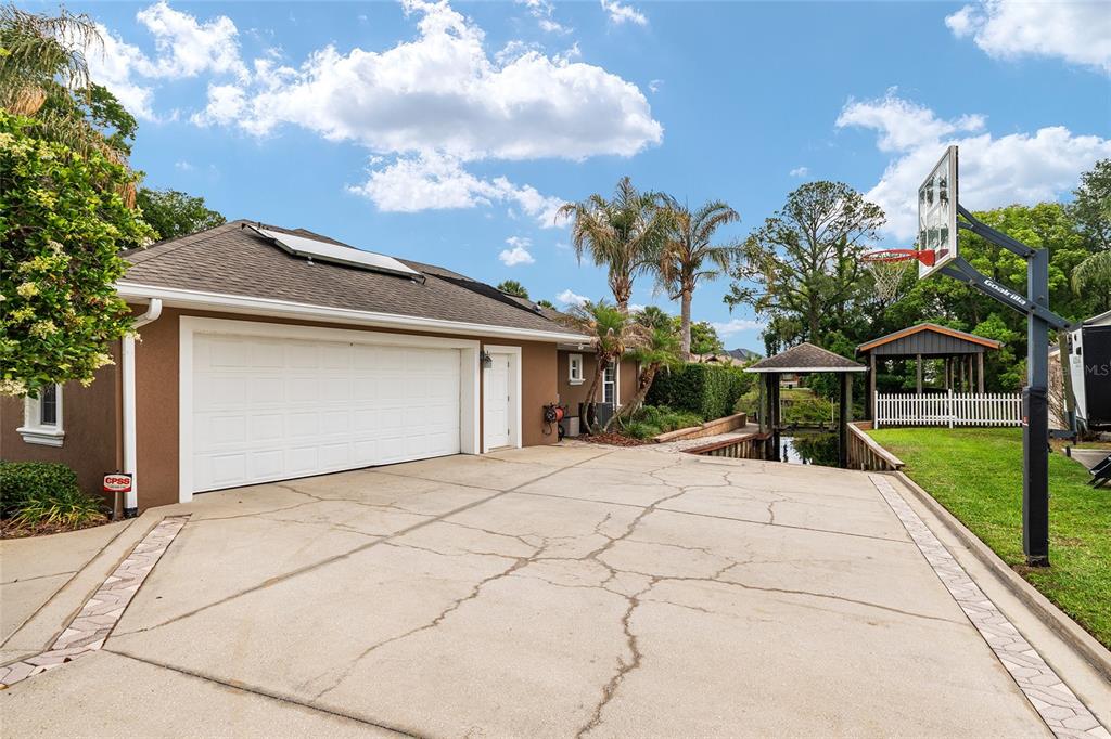 A concrete driveway leads to a two-car garage with a basketball hoop and water access — 29 SE OCALE WAY, SUMMERFIELD, FL