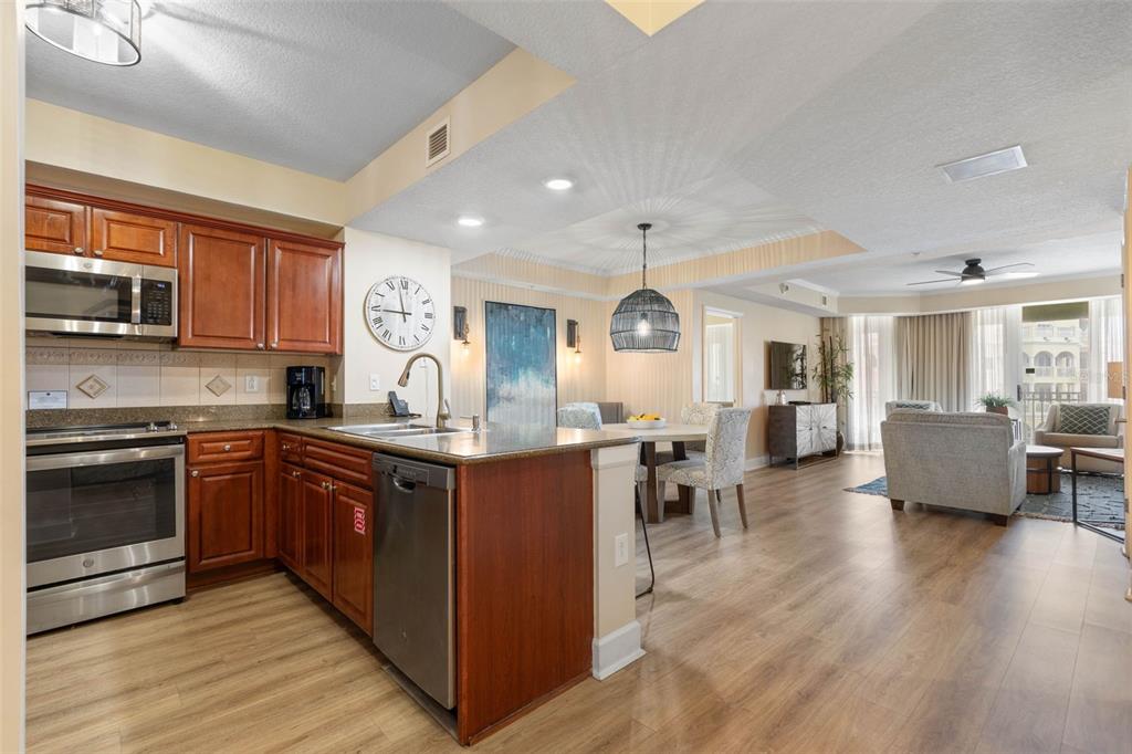 A kitchen with wood cabinets and stainless steel appliances opens to a dining and living area — 200 OCEAN CREST DRIVE UNIT 906, PALM COAST, FL