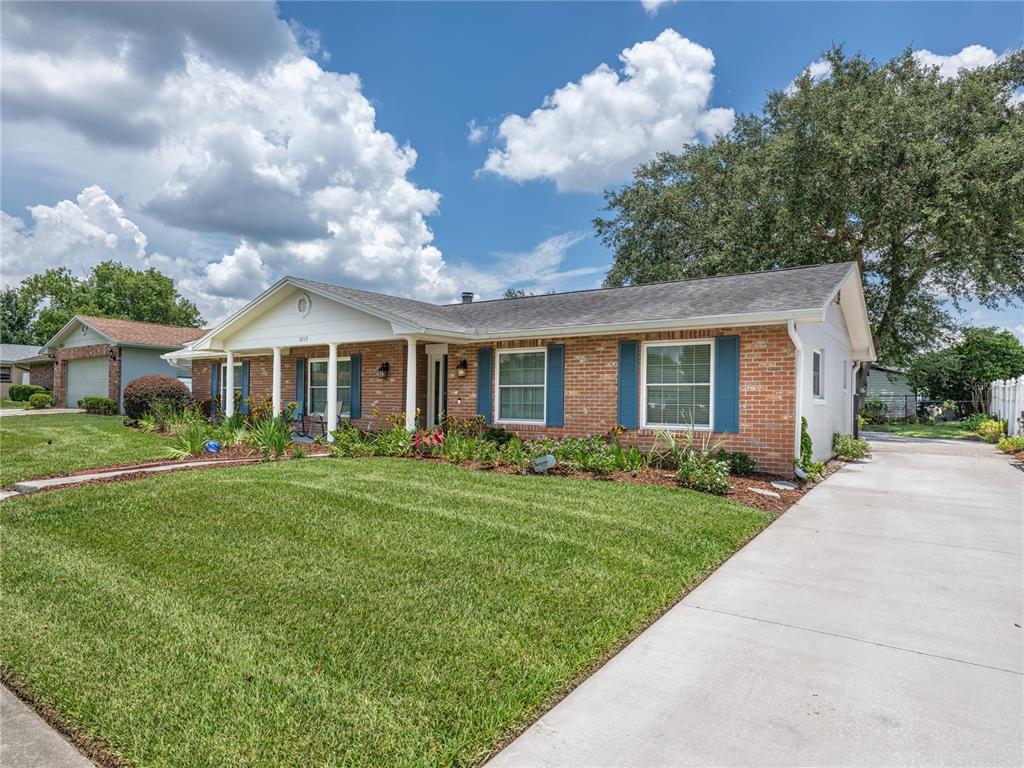 A single-story brick house with a front porch, blue shutters, and a concrete driveway — 3219 HIDALGO DRIVE, ORLANDO, FL