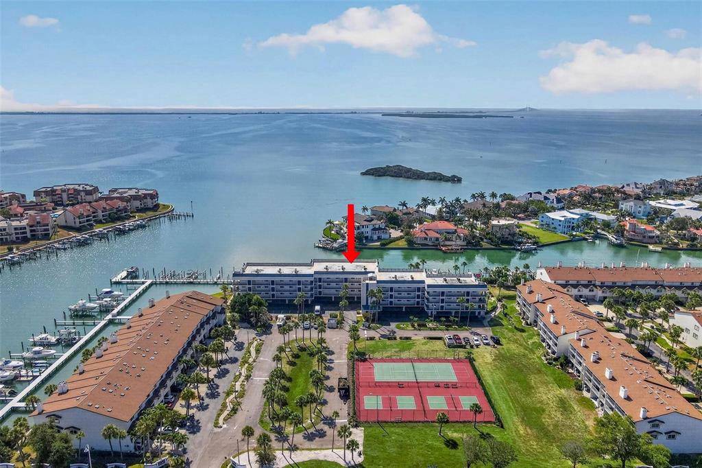 An aerial view shows a multi-story apartment building with a marina and tennis courts — 363 PINELLAS BAYWAY S UNIT 42, ST PETERSBURG, FL