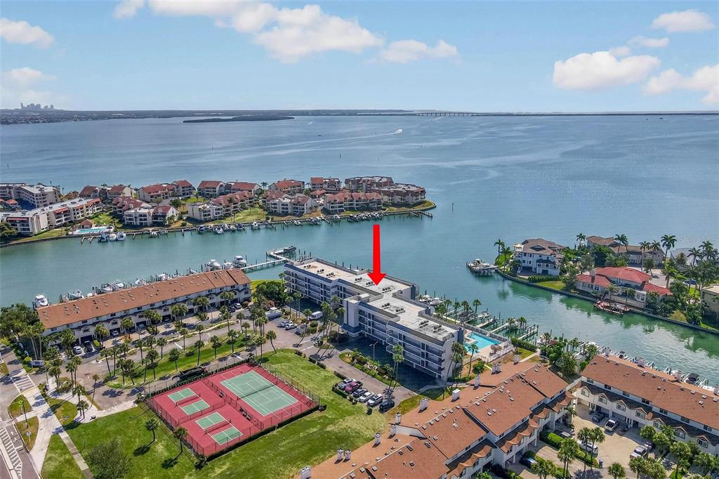 An aerial view shows a multi-story waterfront condominium complex with a tennis court and boat slips — 363 PINELLAS BAYWAY S UNIT 42, ST PETERSBURG, FL