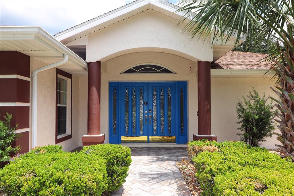 The exterior of a house features a blue double front door under a covered entryway — 21300 ROYAL ST GEORGES LANE, LEESBURG, FL