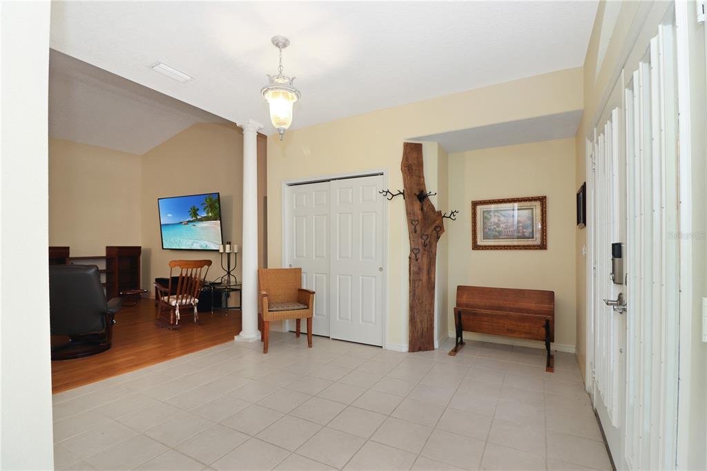 An entryway with tiled floors, a wooden coat rack, and a view into a living area — 21300 ROYAL ST GEORGES LANE, LEESBURG, FL